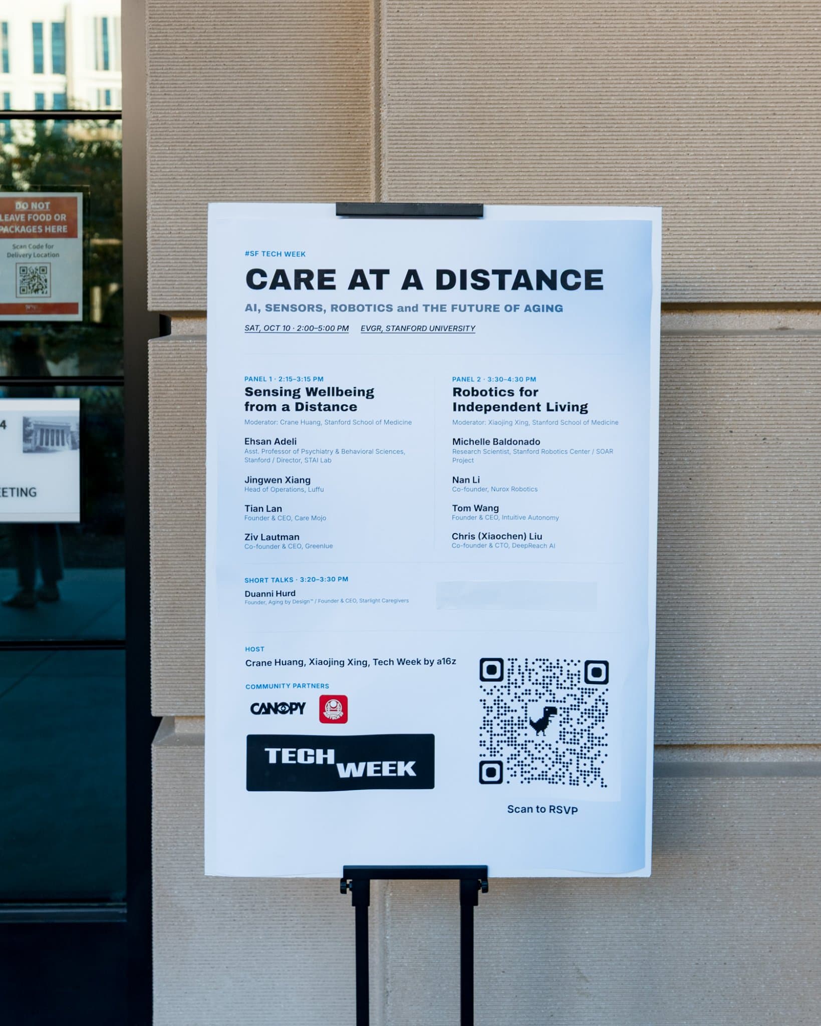Care at a Distance event poster with the panel lineup on an easel outside the venue at Care at a Distance: AI, Sensors, Robotics and the Future of Aging, SF Tech Week 2026 at EVGR, Stanford University by JY Studio