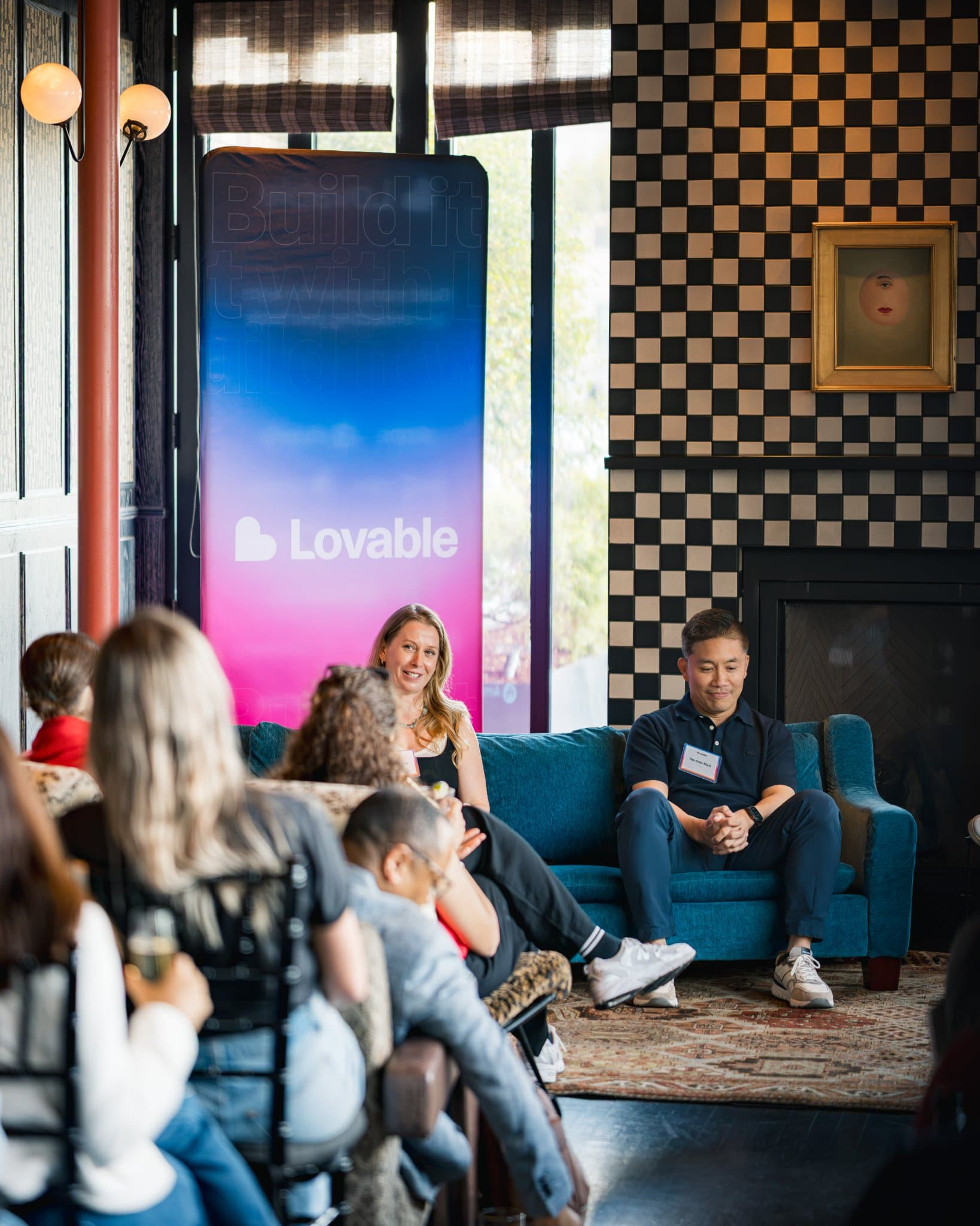 Audience view of the panel with Lovable banners and the checkerboard fireplace at Lovable's When Everyone Can Build panel in San Francisco by JY Studio