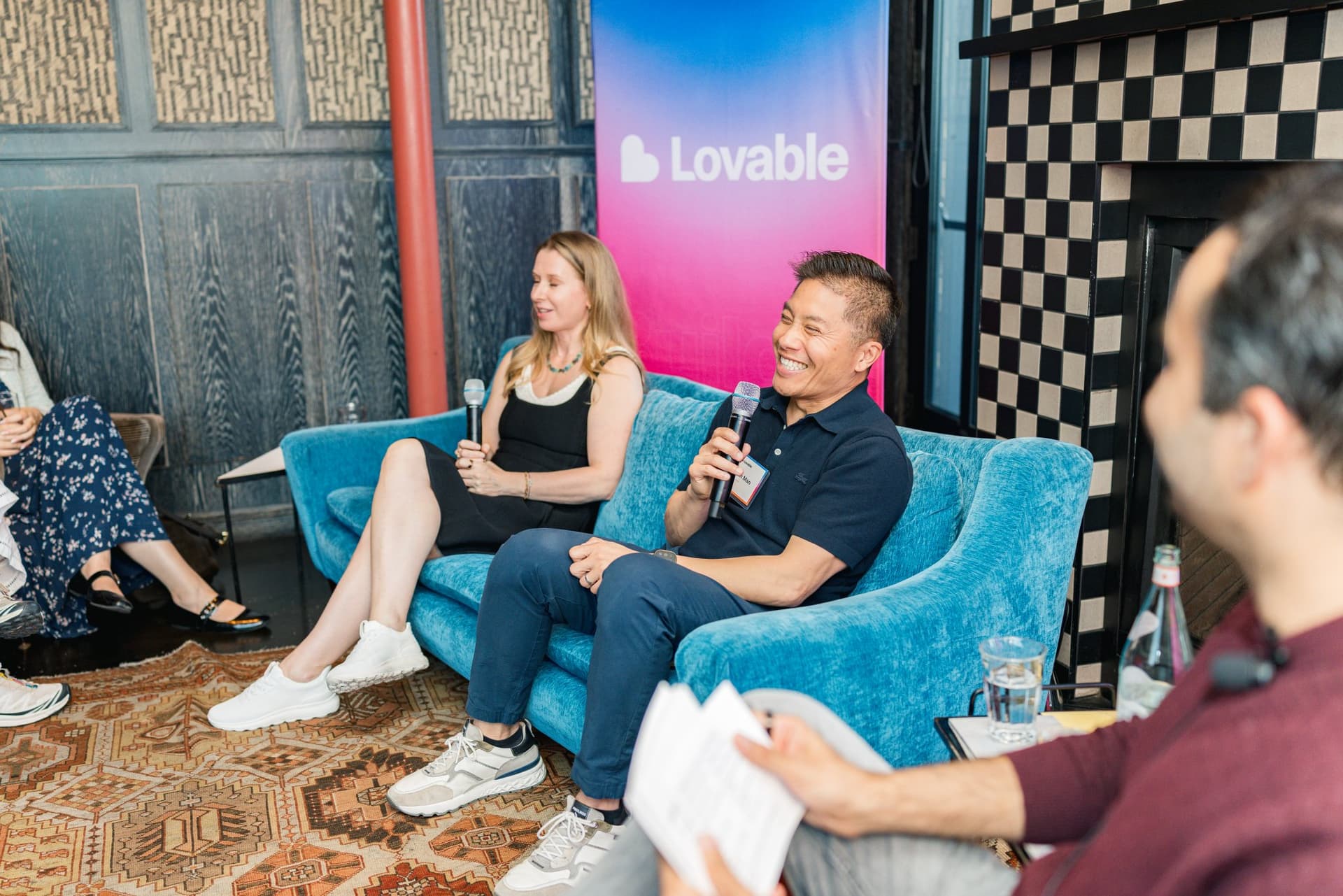 Herman Man speaking into the microphone beside Elena Verna as the moderator reads questions at Lovable's When Everyone Can Build panel in San Francisco by JY Studio