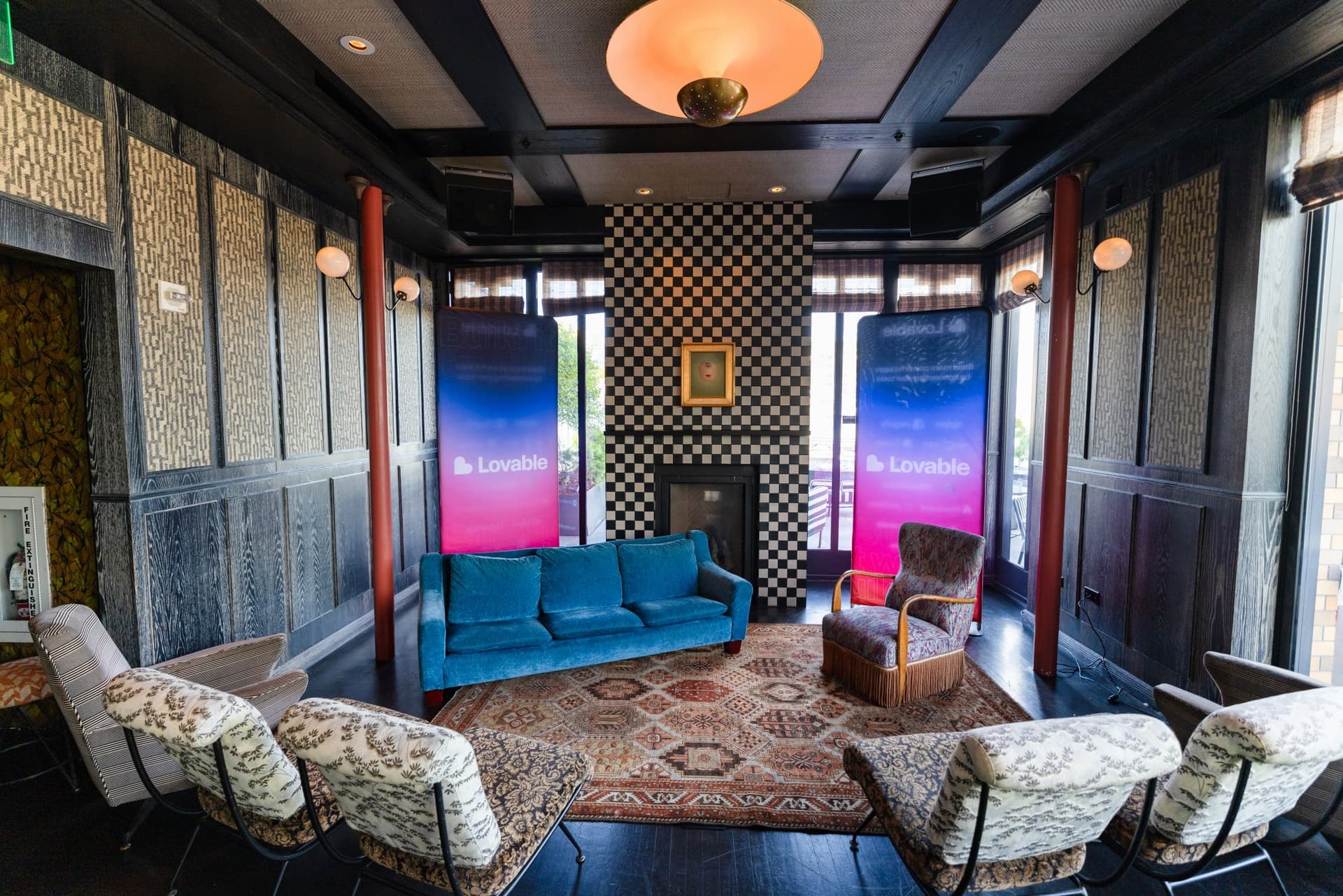 Panel stage setup with a teal sofa, vintage rug and two Lovable banners at Lovable's When Everyone Can Build panel in San Francisco by JY Studio