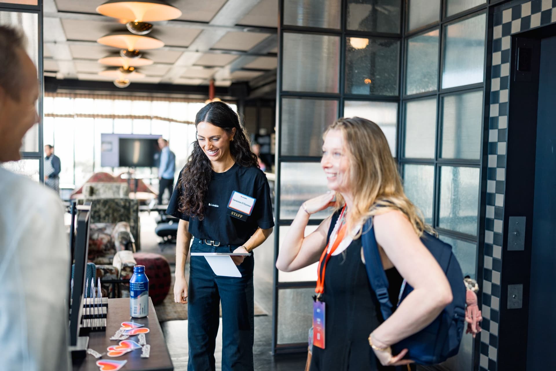 Lovable team members chatting with an arriving guest at Lovable's When Everyone Can Build panel in San Francisco by JY Studio