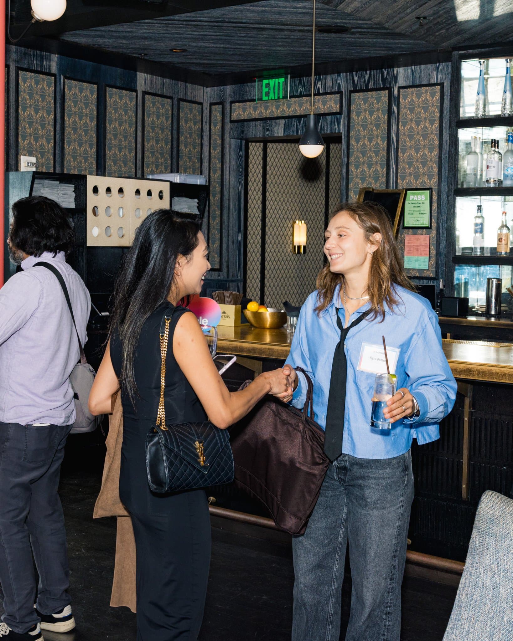 Two guests greeting each other with drinks at the bar at Lovable's When Everyone Can Build panel in San Francisco by JY Studio