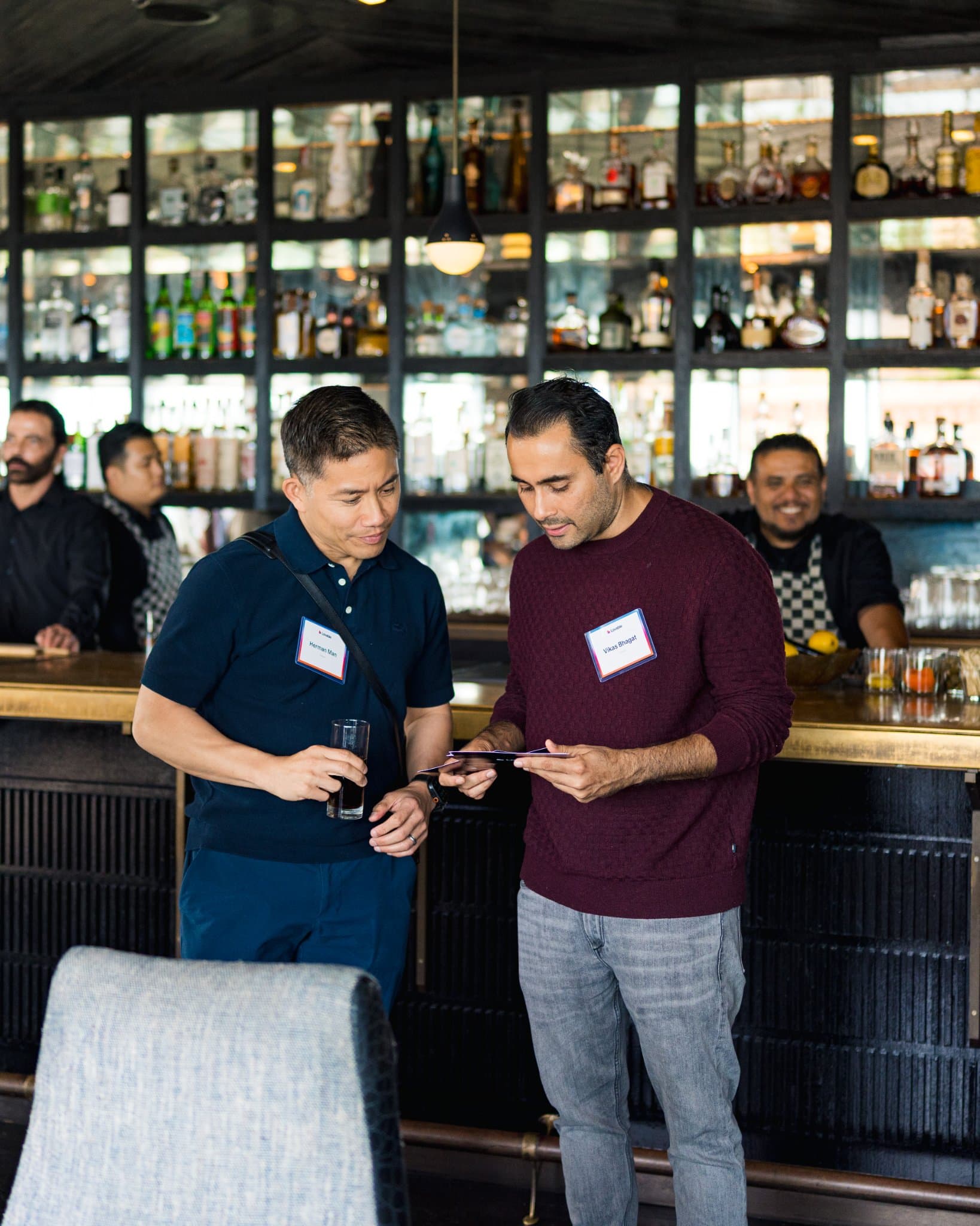 Two guests looking at a phone together at the bar at Lovable's When Everyone Can Build panel in San Francisco by JY Studio