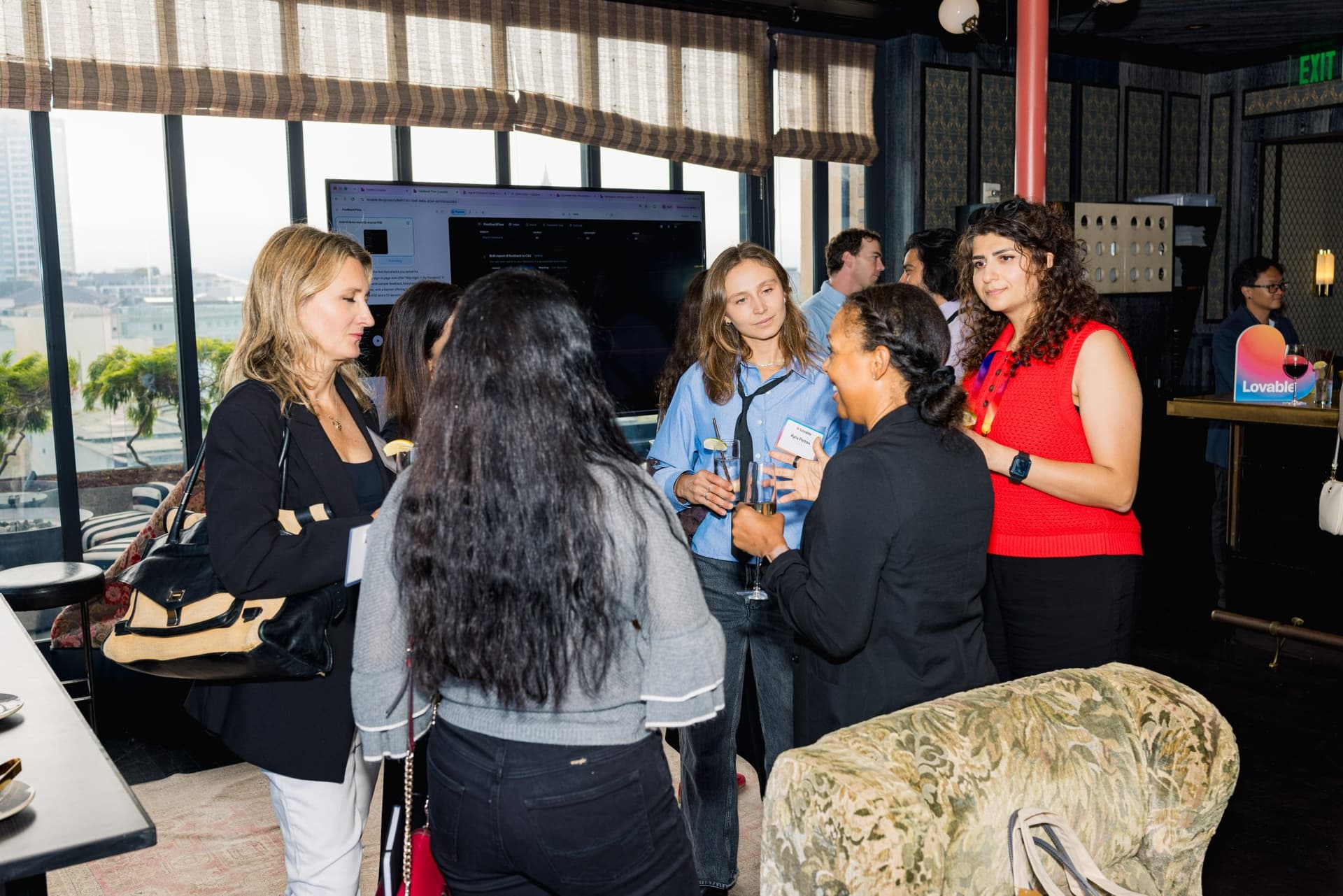 Group of guests chatting by the windows during the reception at Lovable's When Everyone Can Build panel in San Francisco by JY Studio