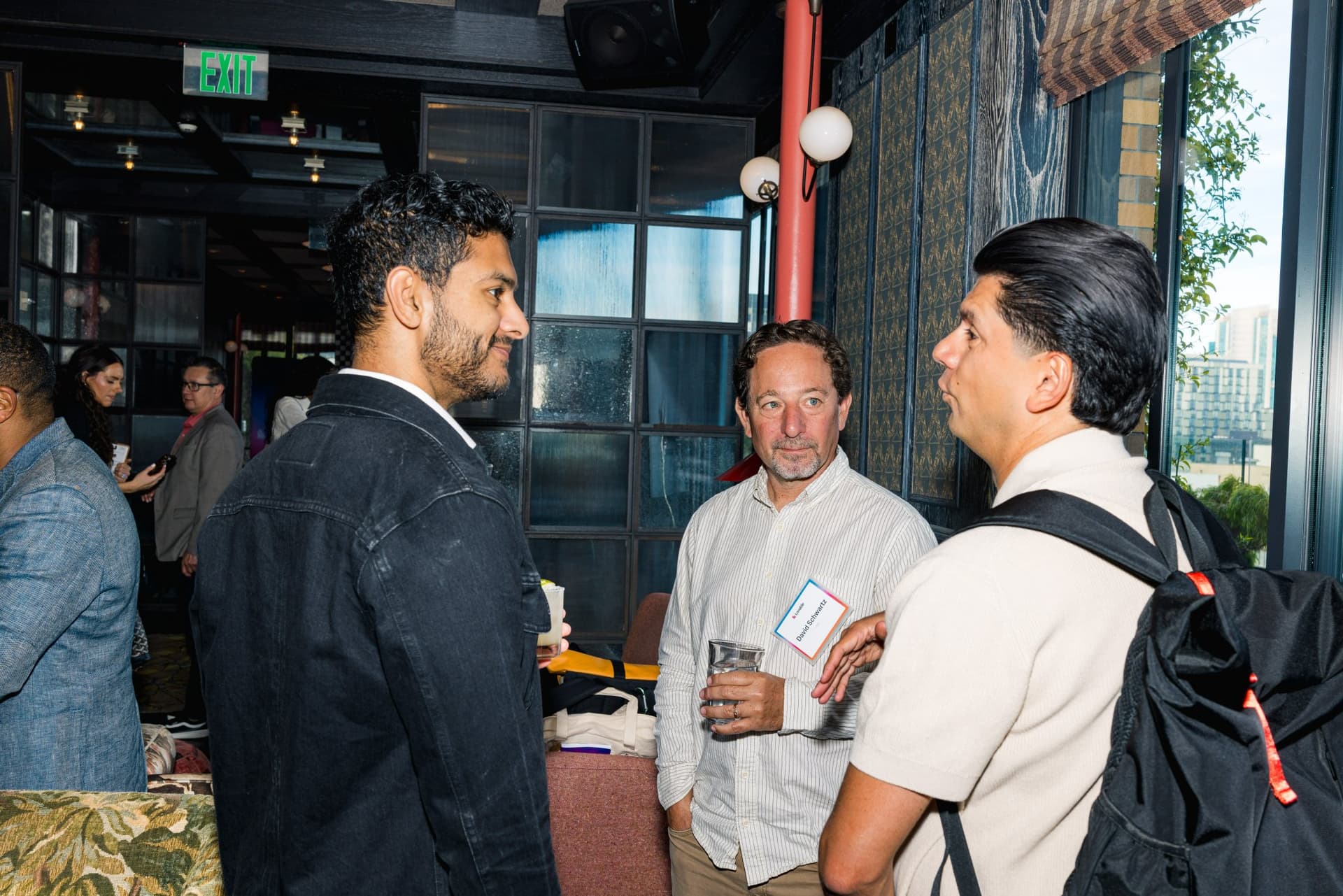 Three guests in conversation near the rooftop windows at Lovable's When Everyone Can Build panel in San Francisco by JY Studio