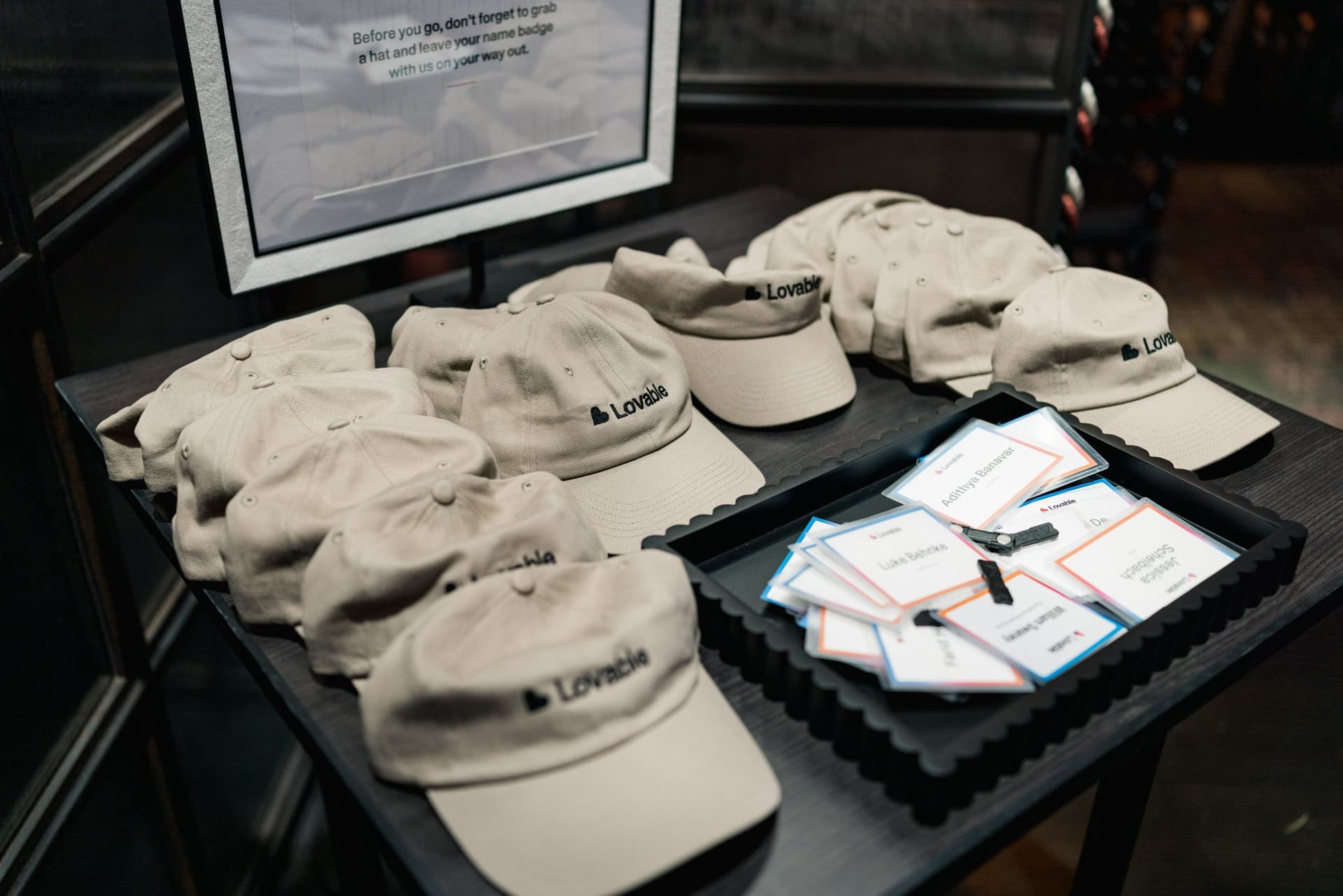 Lovable branded caps and name badges on the swag table at Lovable's When Everyone Can Build panel in San Francisco by JY Studio