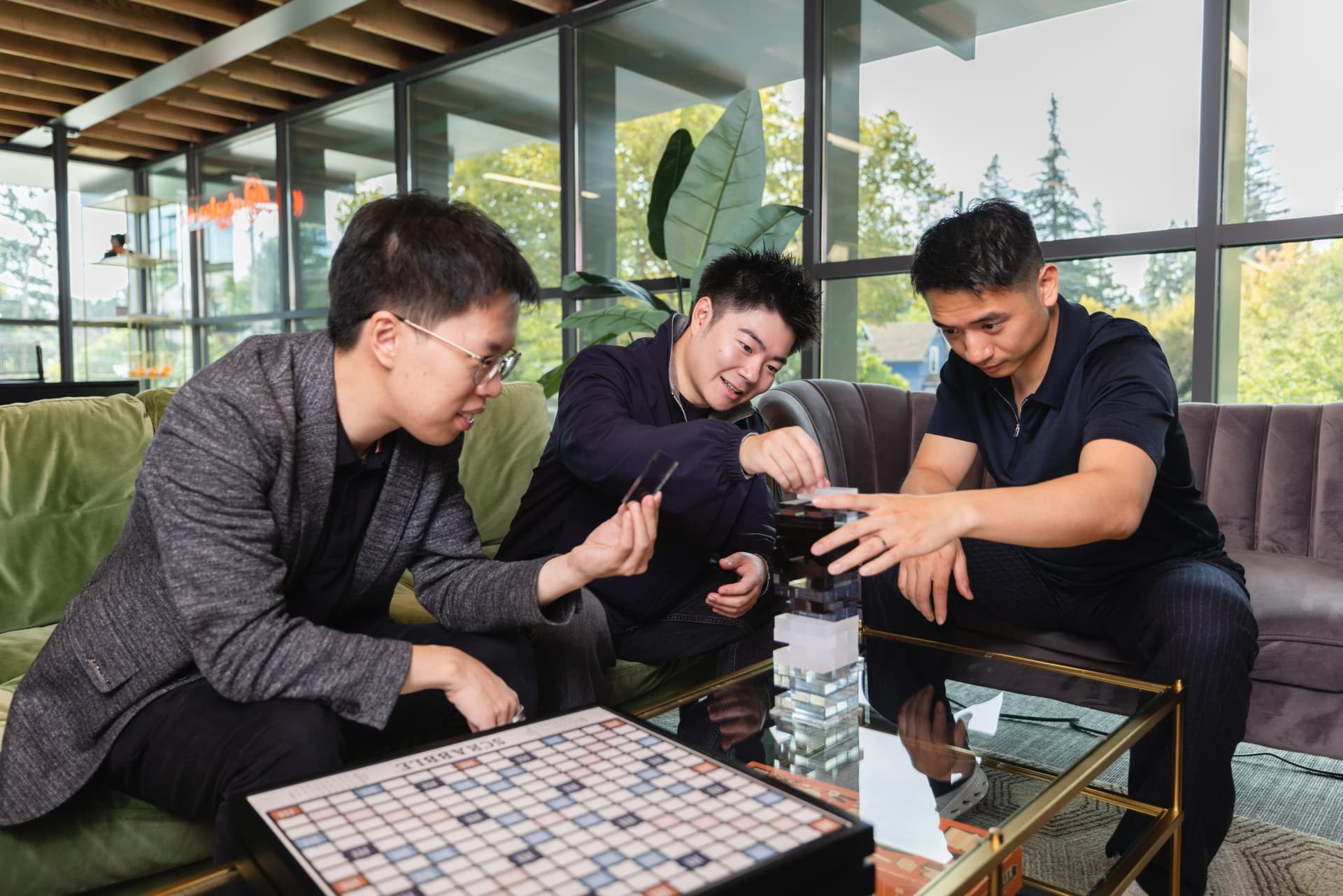 Abaka AI co-founders candid lifestyle portrait playing a stacking-block game in a modern Mountain View office lounge, founder photography for press kit and funding announcements by JY Studio