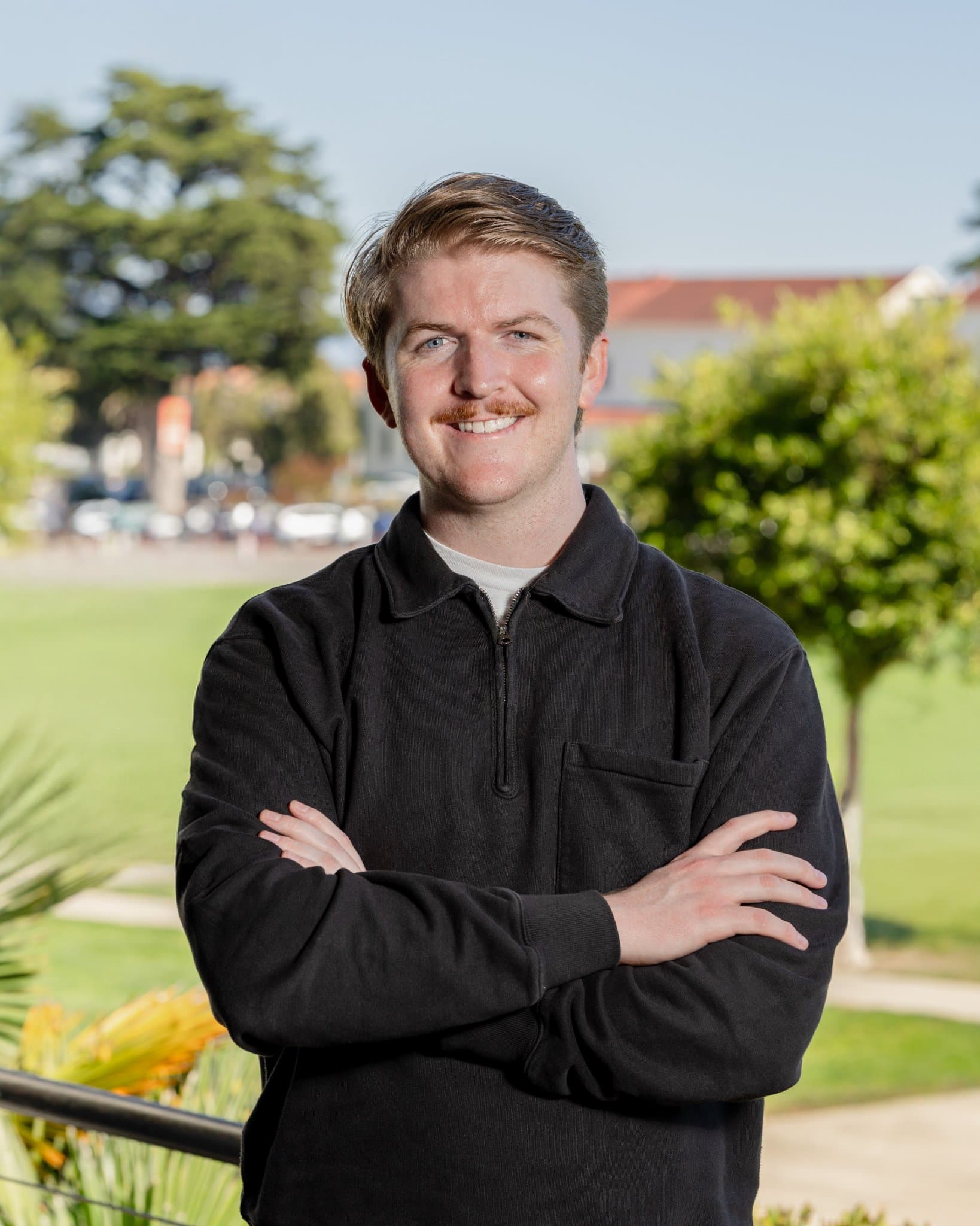 General Compute team member confident crossed-arms outdoor headshot in a black quarter-zip with soft natural light, on-location startup headshot photography in San Francisco for company website and LinkedIn by JY Studio
